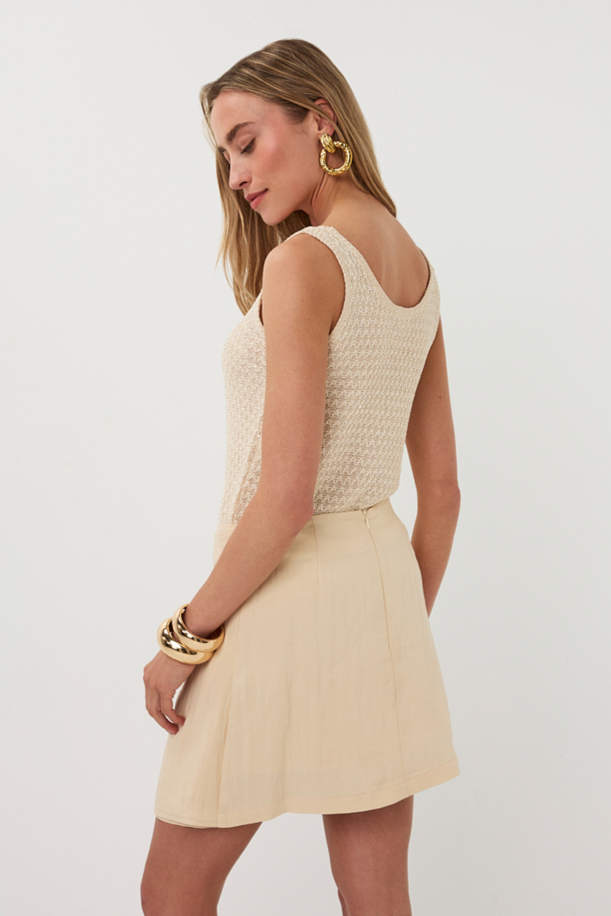 Woman wearing a beige sleeveless top and skirt set on a white background