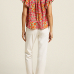 back of woman in floral blouse and white denim on white background 