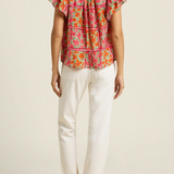 back of woman in floral blouse and white denim on white background 