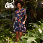 Woman in a floral dress standing among green plants