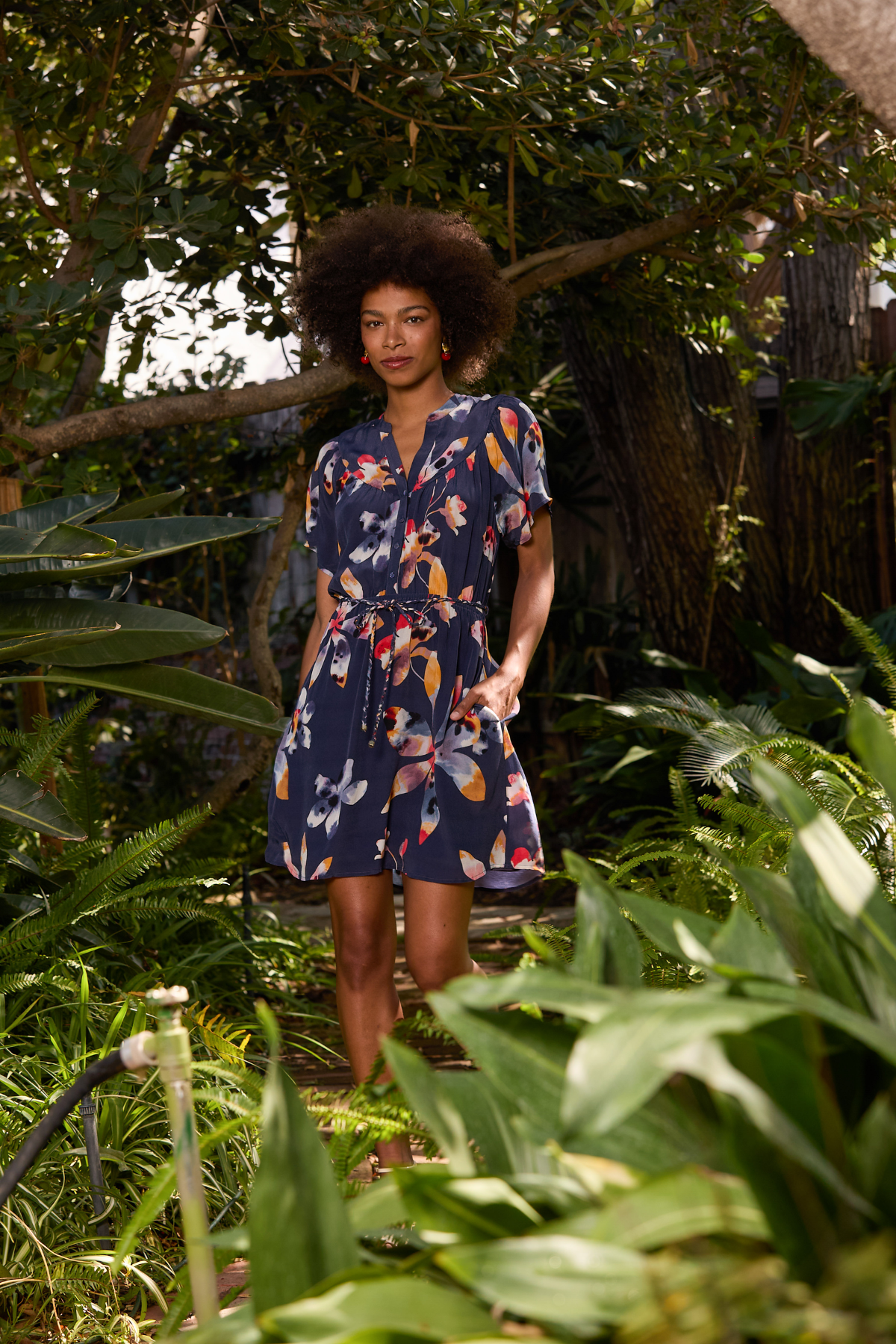 Woman in a floral dress standing among green plants