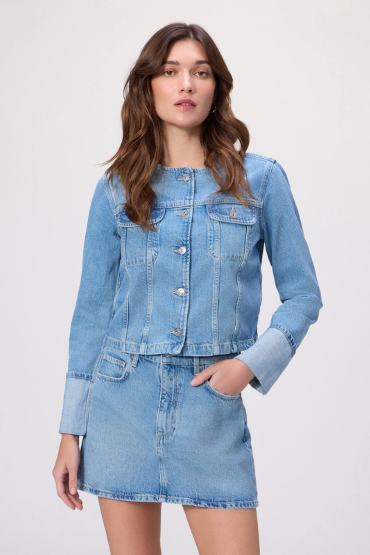 Woman wearing a denim jacket and skirt on a white background