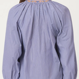 Purple blouse with embroidered neckline worn by a person on a white background