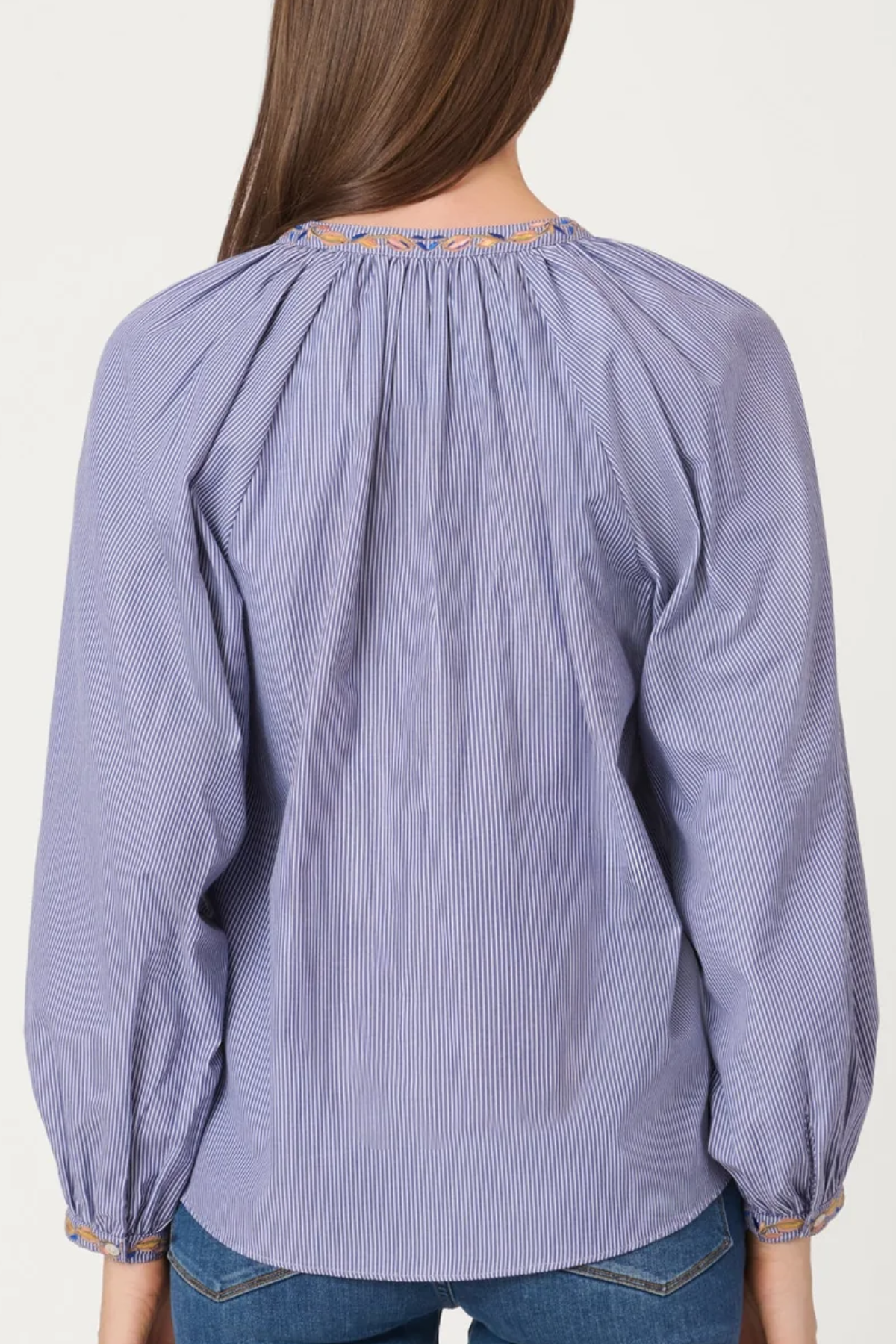 Purple blouse with embroidered neckline worn by a person on a white background