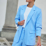 Woman wearing a light blue pinstripe suit with a white top outdoors.