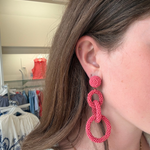 Model wearing coral pink linked drop earrings featuring three open circular shapes in a lightweight statement design.