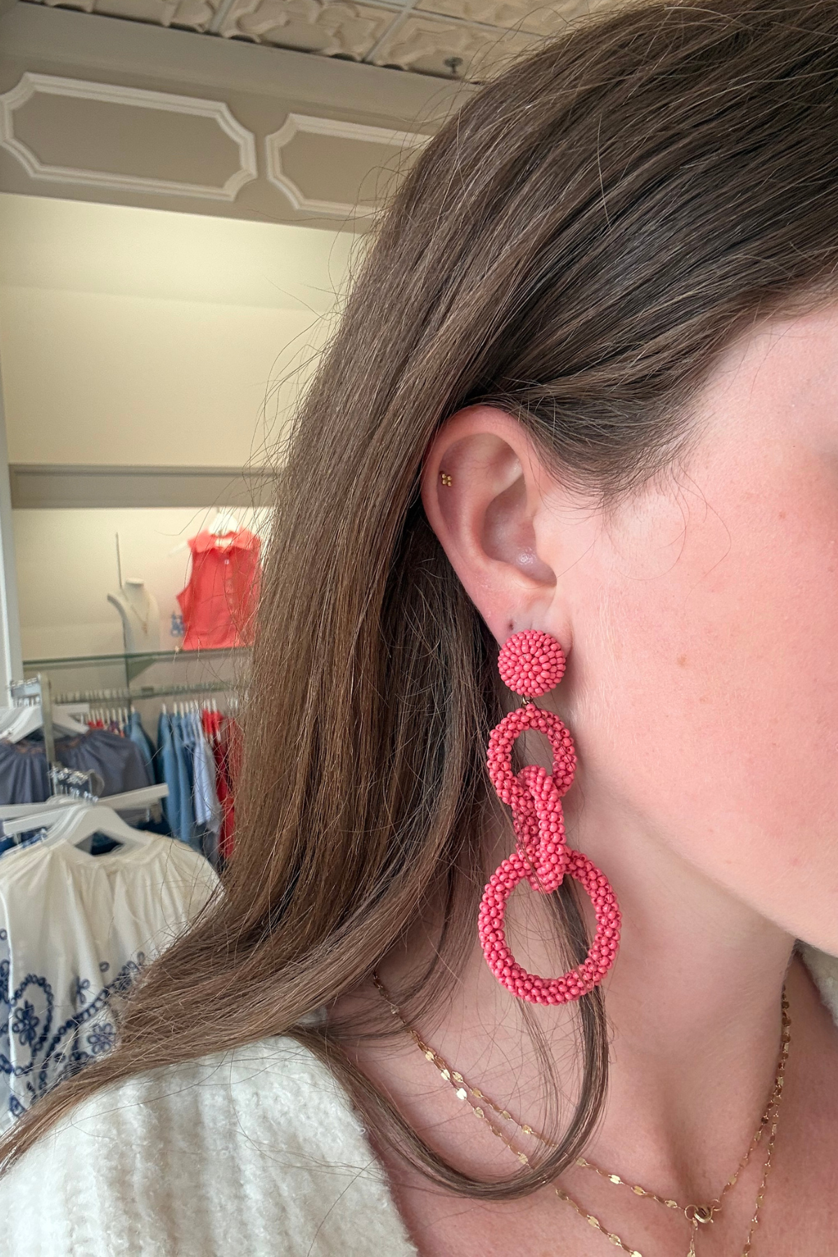 Model wearing coral pink linked drop earrings featuring three open circular shapes in a lightweight statement design.