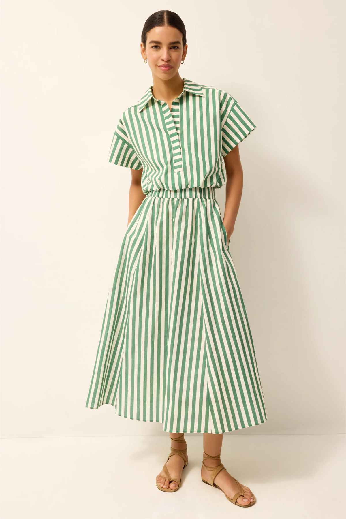 Woman wearing a green and white striped skirt on a plain background