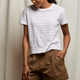 Woman wearing a striped shirt and brown shorts against a neutral background