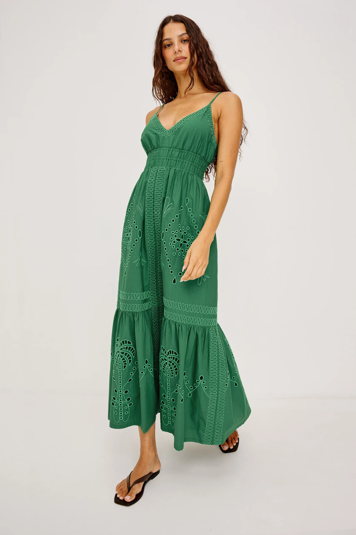 Woman wearing a green dress with intricate patterns on a white background