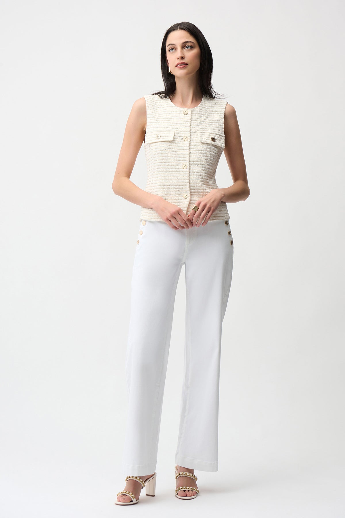 Woman wearing a sleeveless beige top and white pants on a white background