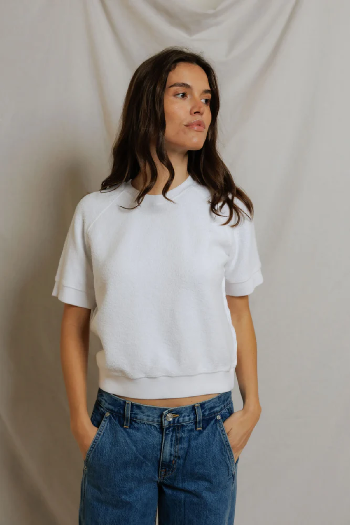 woman in white short sleeve top and denim on draped background 