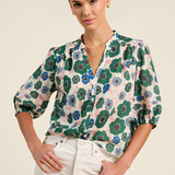 Woman wearing a floral blouse with green and blue patterns on a beige background