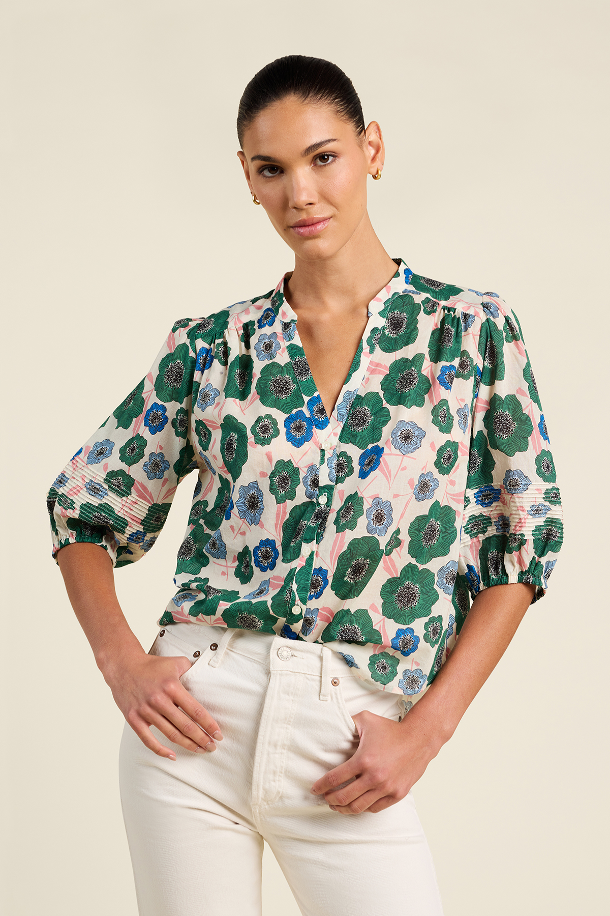 Woman wearing a floral blouse with green and blue patterns on a beige background