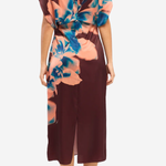 A woman modeling a midi dress from the back, featuring a deep burgundy base with a large peach and blue floral print on the upper back and shoulder area.