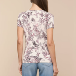 Woman wearing a floral t-shirt and blue jeans on a beige background