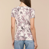 Woman wearing a floral t-shirt and blue jeans on a beige background