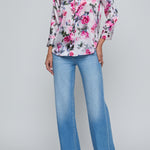Person wearing a floral blouse and blue jeans on a gray background