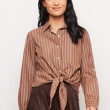 A woman modeling a brown and beige vertically striped button-down shirt tied at the waist, paired with dark brown pants, against a plain light gray background.