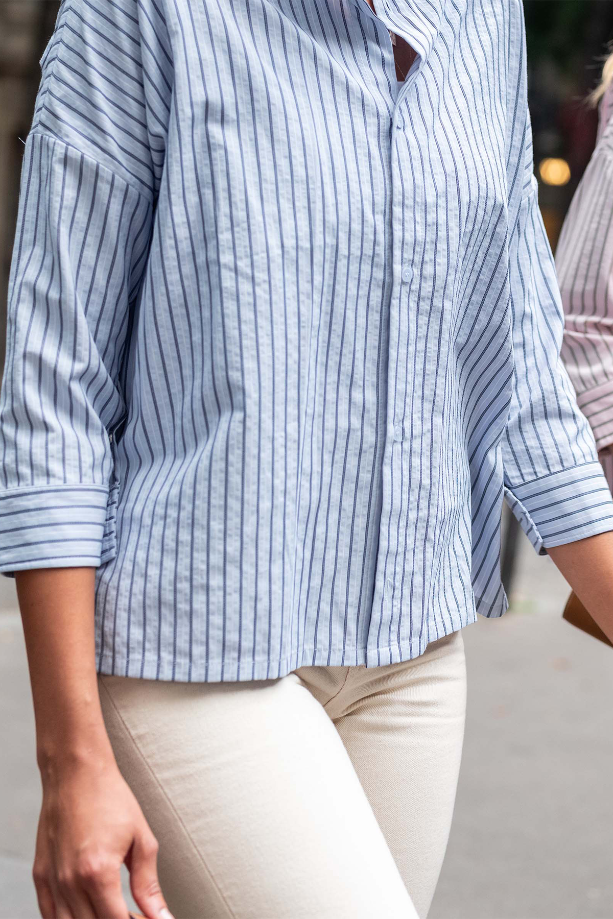 Close-up of a person wearing a blue and white striped shirt with rolled-up sleeves.