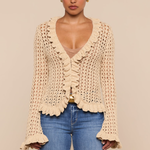 Woman wearing a beige crochet cardigan and blue jeans on a beige background