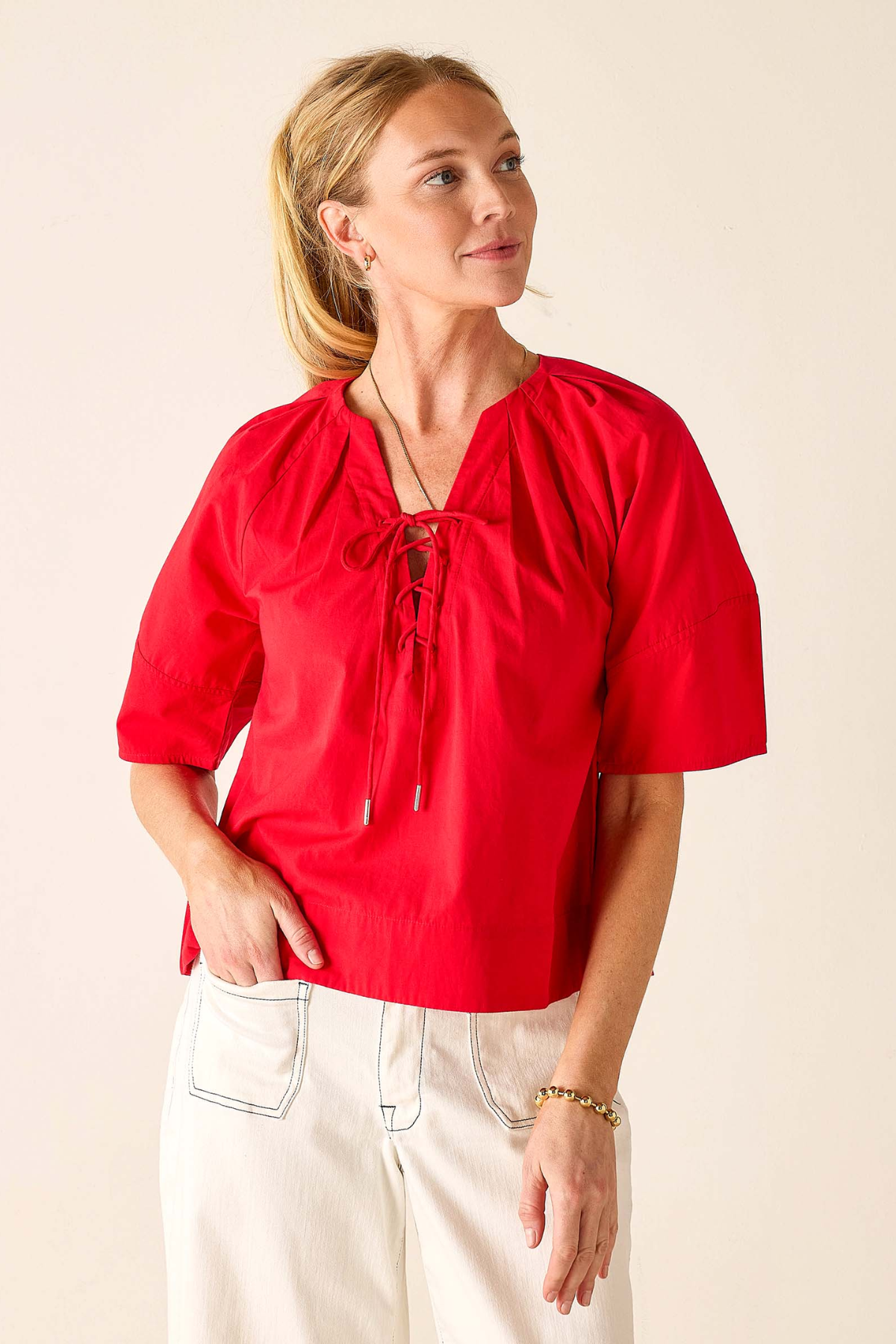 Woman wearing a red blouse with a beige background
