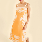 Woman wearing a yellow dress with white floral patterns on a beige background