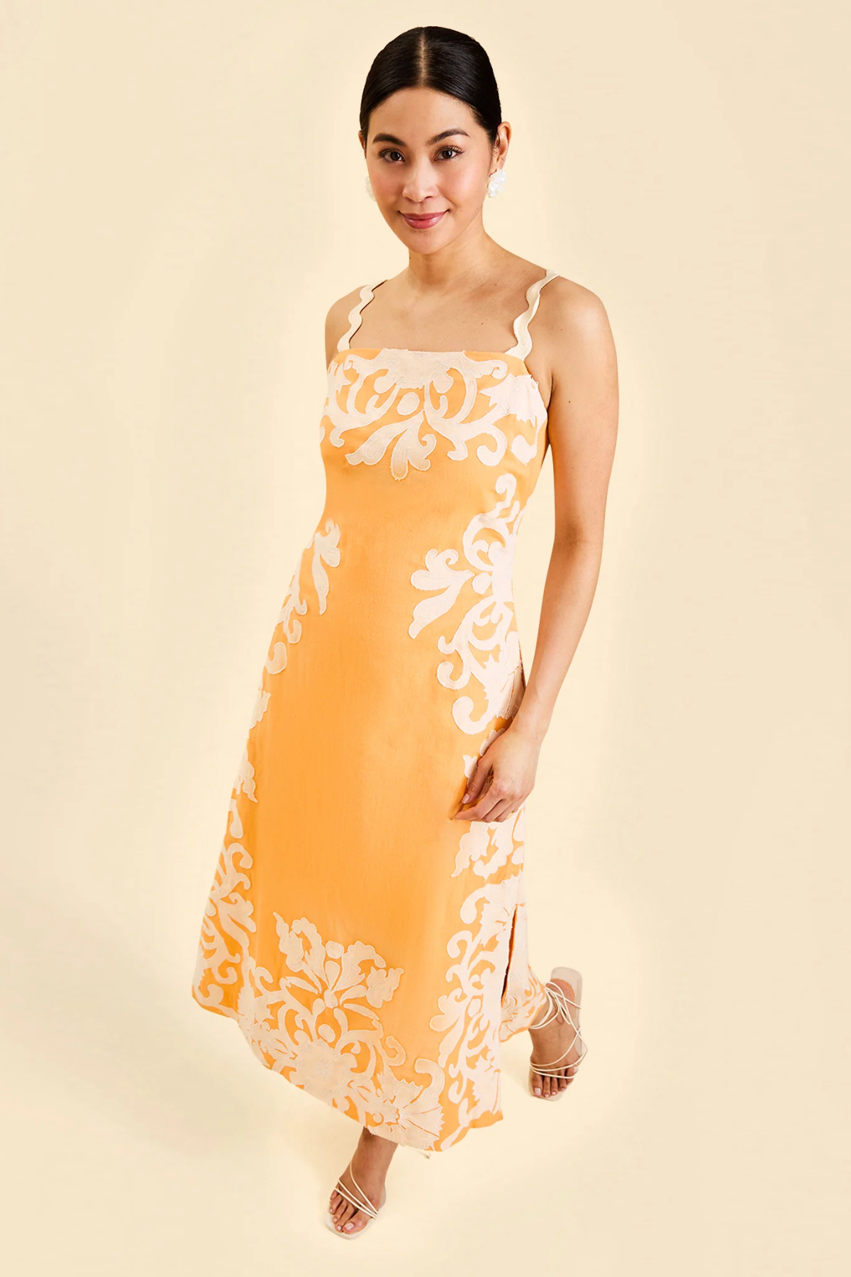 Woman wearing a yellow dress with white floral patterns on a beige background