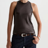 Woman wearing a brown sleeveless top and dark jeans on a white background