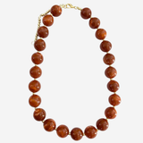 A beaded necklace made of polished round brown gemstone beads with a gold-tone clasp, displayed on a light gray background.