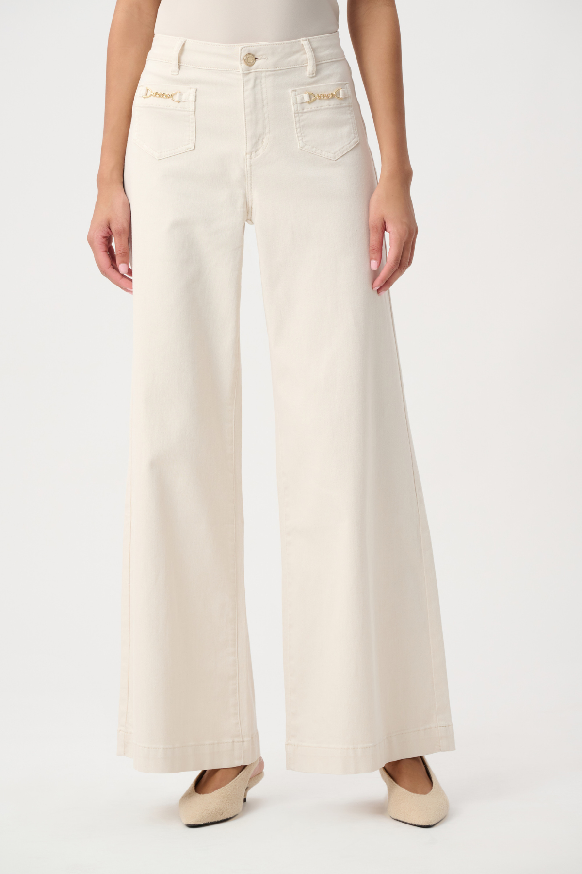 A model wearing a pair of off-white wide-leg jeans with gold-tone hardware on the front pockets, paired with beige flats, against a plain white studio background.