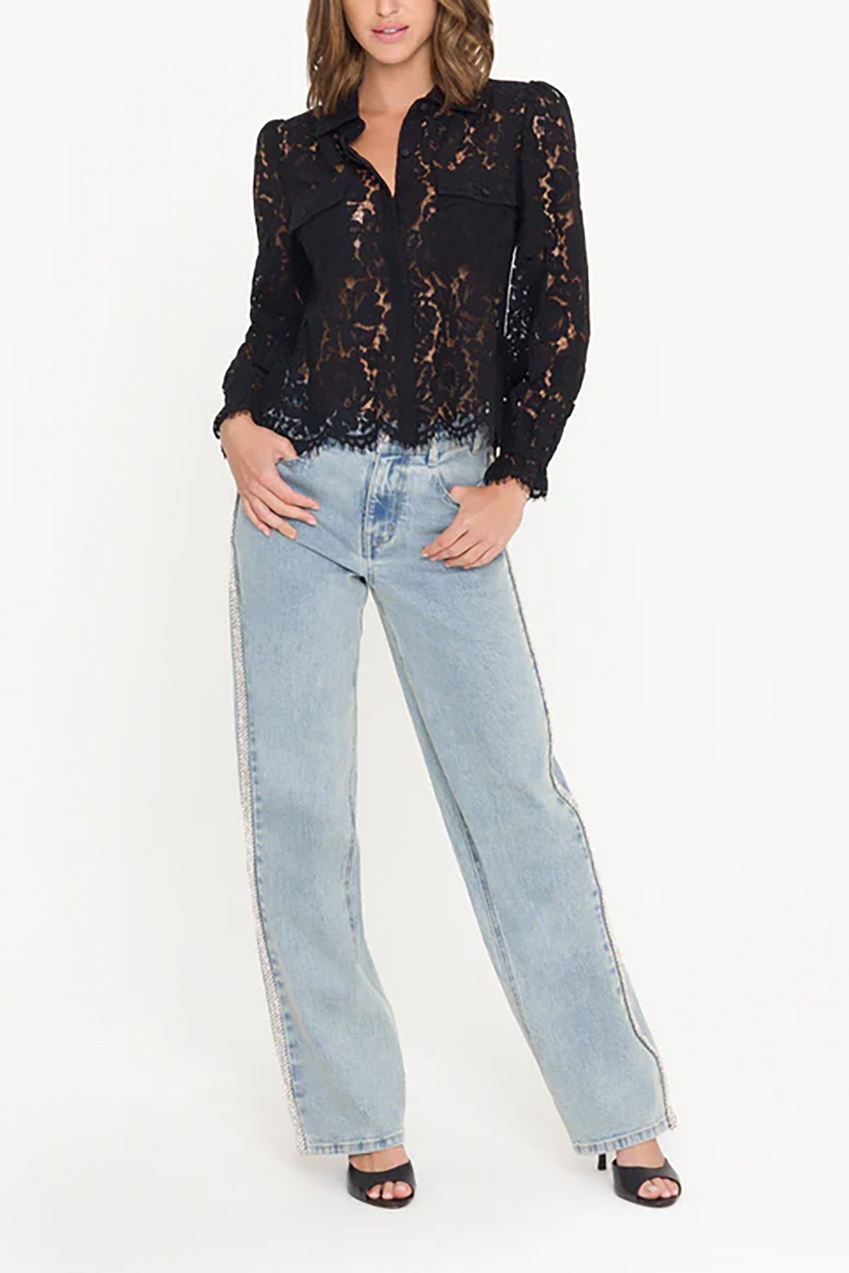 Woman wearing a black lace blouse and light blue jeans on a white background