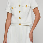 White outfit with gold buttons on a plain background