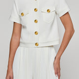 White outfit with gold buttons on a plain background