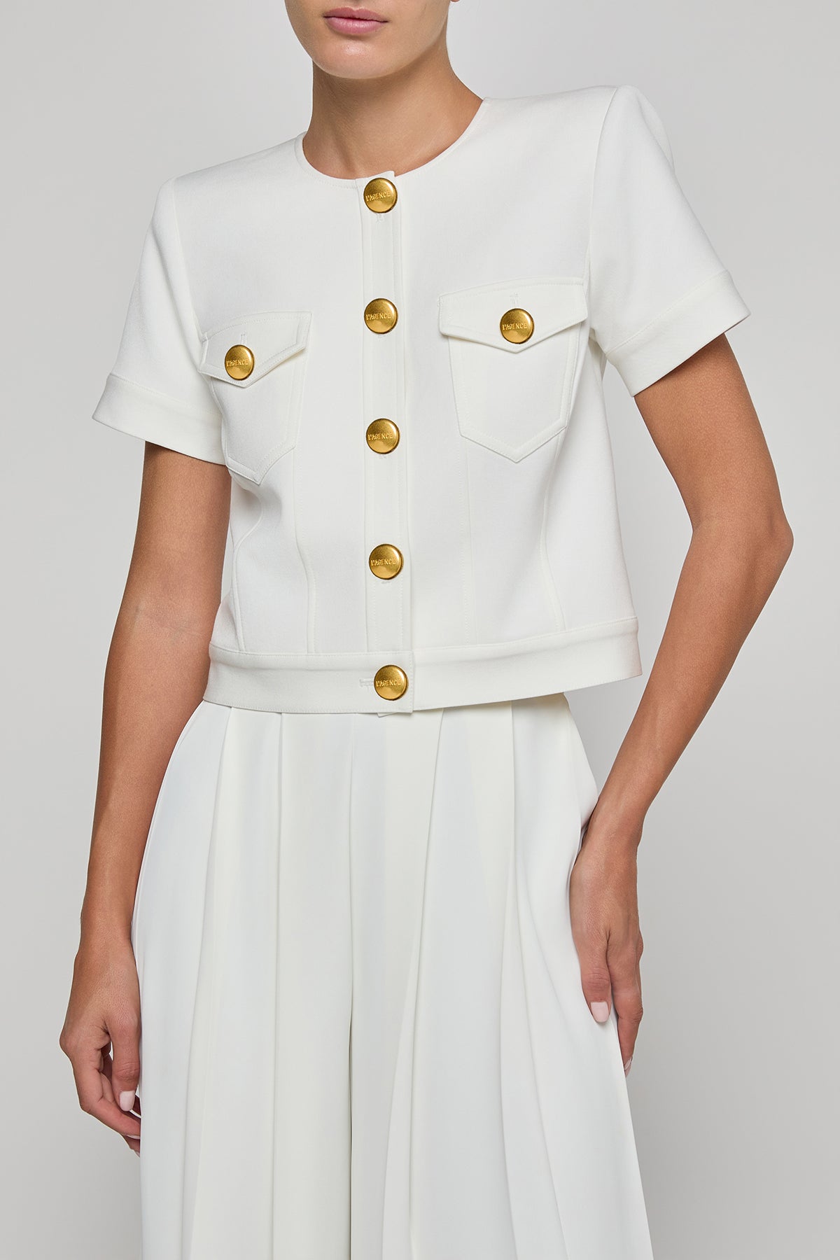 White outfit with gold buttons on a plain background