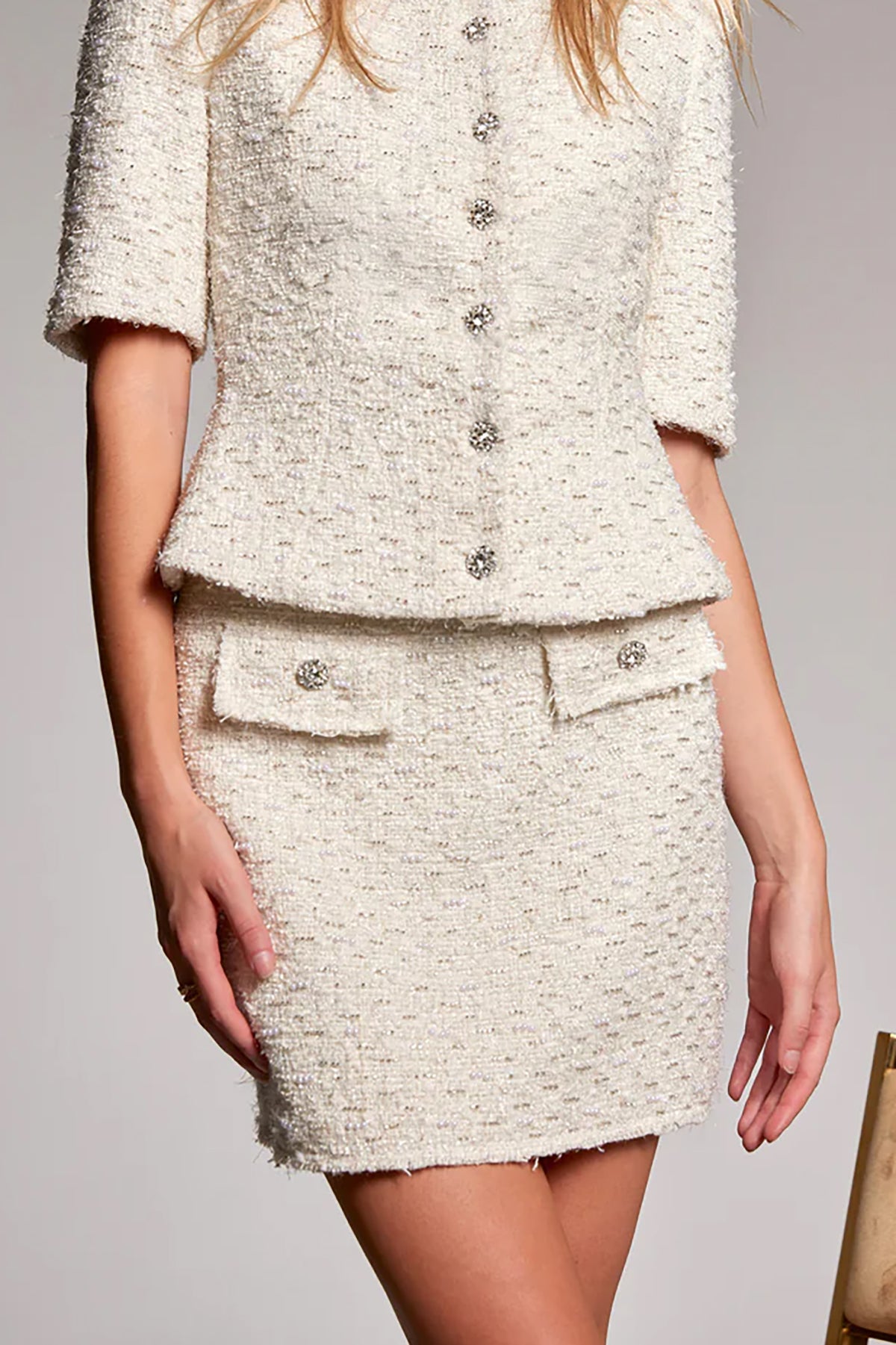 White tweed suit with buttons on a plain background