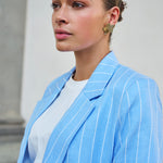 Woman wearing a light blue pinstripe blazer with a neutral background