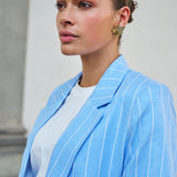 Woman wearing a light blue pinstripe blazer with a neutral background