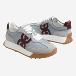 A pair of low-top sneakers in light blue suede and mesh, featuring a large dark burgundy 'G' logo on the side, white laces, a white midsole, and a brown gum outsole, shown against a light gray background.