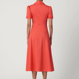 Woman wearing a coral dress on a white background
