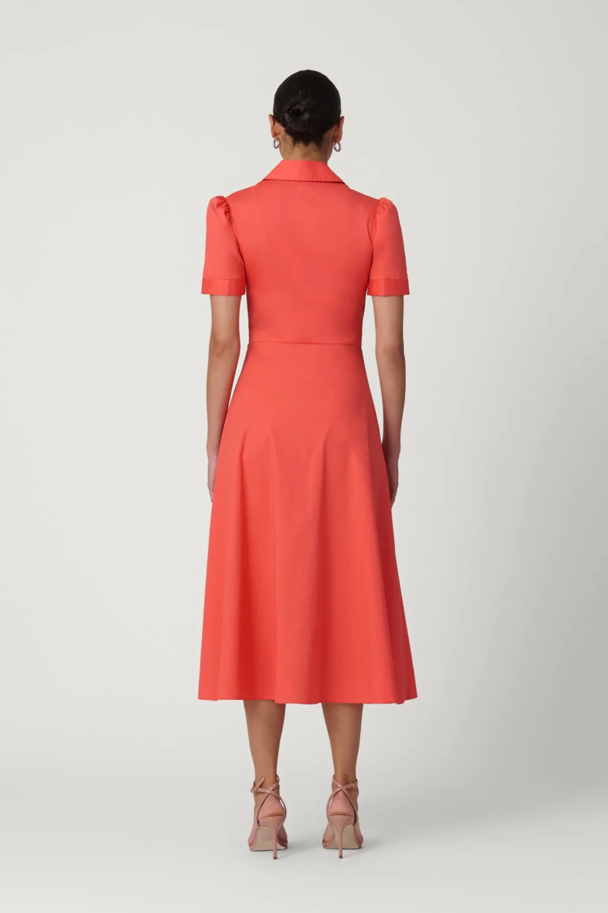 Woman wearing a coral dress on a white background