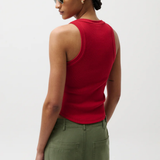 Woman wearing a red sleeveless top and green pants against a white background