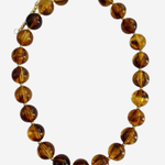 A beaded necklace made of polished round amber-brown glass beads with a small gold clasp, shown on a plain light gray background.
