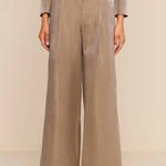 A model wearing a taupe-beige double-breasted wide-leg trouser set with gold buttons, shown from the chest down against a neutral beige background.