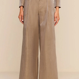 A model wearing a taupe-beige double-breasted wide-leg trouser set with gold buttons, shown from the chest down against a neutral beige background.