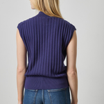 A woman shown from the back wearing a sleeveless, ribbed knit top in a deep purple shade, paired with blue jeans, against a light gray studio background.