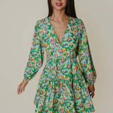 Woman wearing a green floral dress against a plain background