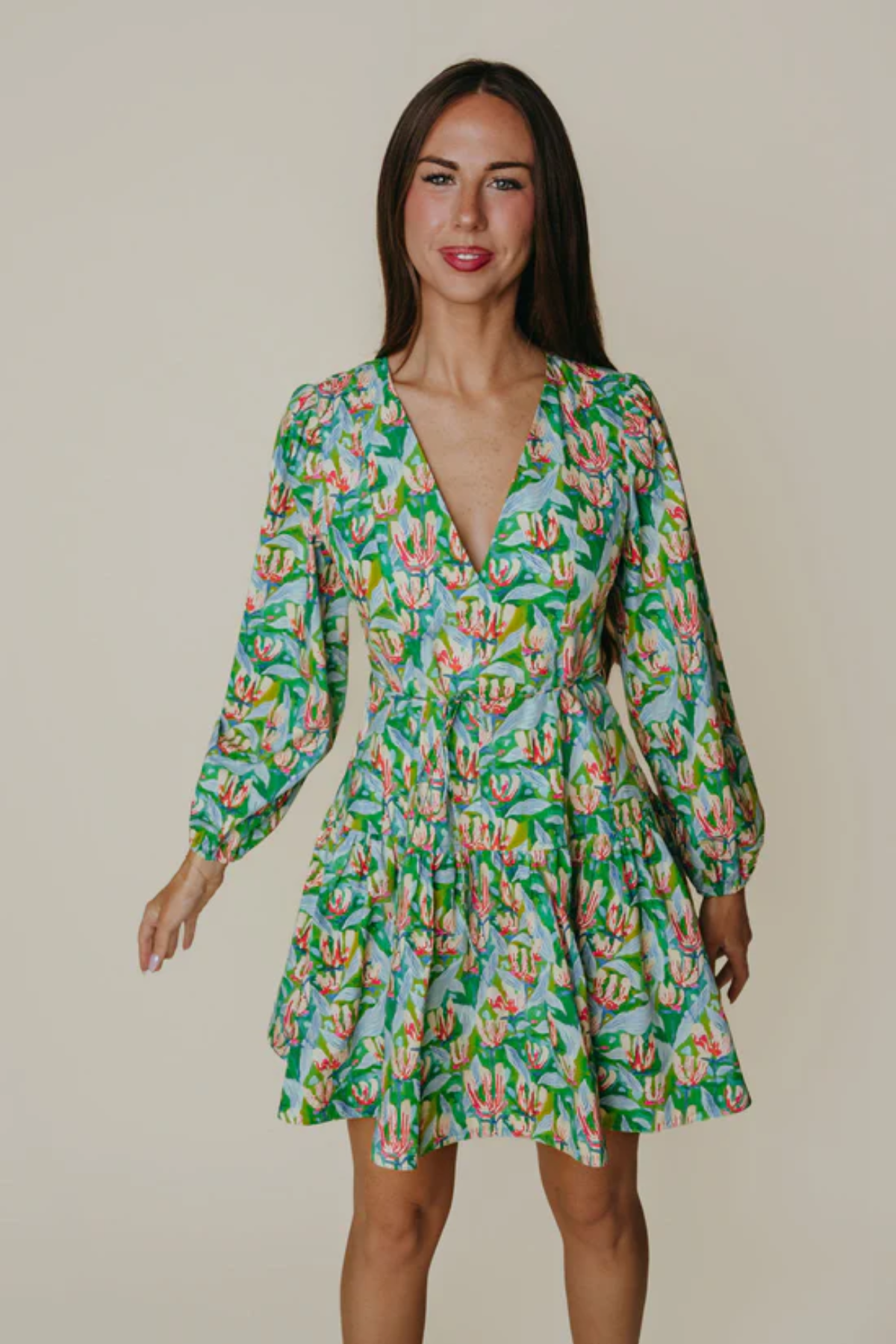 Woman wearing a green floral dress against a plain background