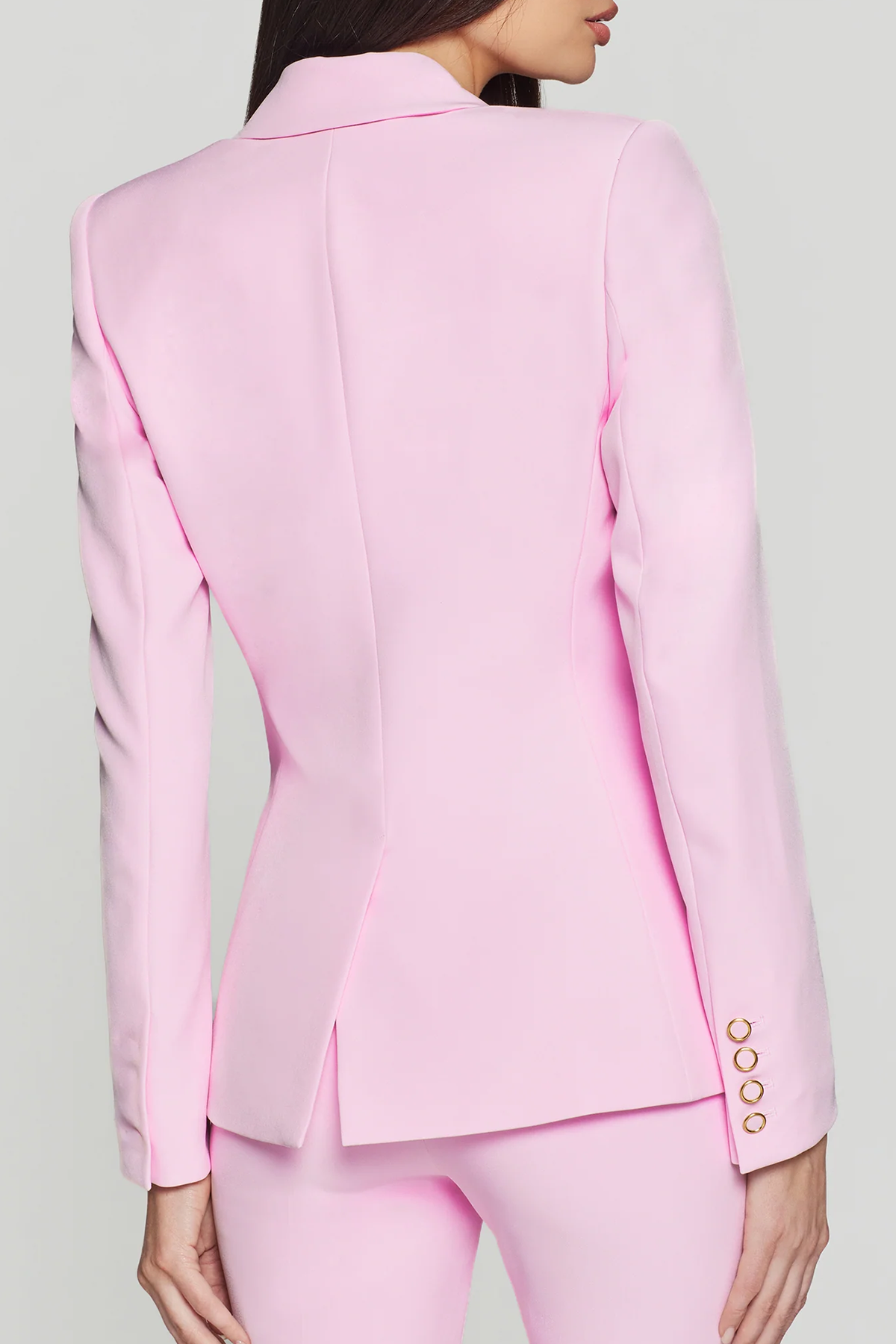 back of woman in pink blazer on white background 