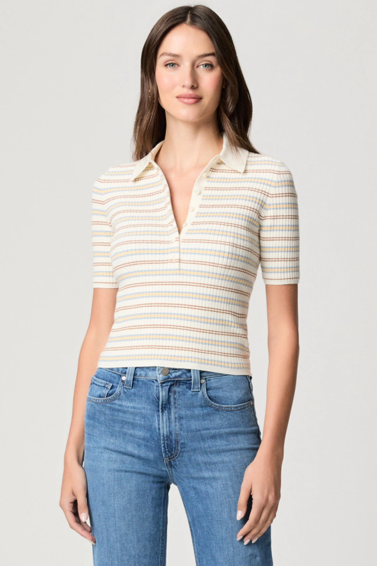 Model wearing a white printed blouse with colorful accents and short sleeves.